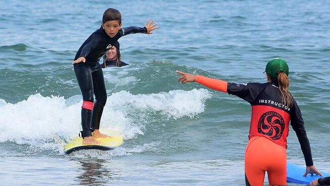 A child learning how to surf with Escuela Cantabra De Surf Quicksilver Roxy