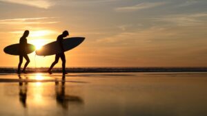 two surfers walking along the beach at sunset during their Fuerteventura surf holiday