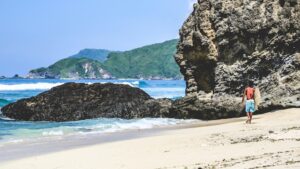 A surfer walking on sand to the water during his Indonesia surf camp experience