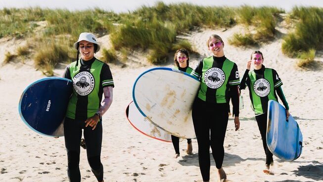 learner surfers walking on the beach with their surfboards