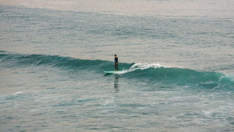 a surfer riding a wave during his time at a Morocco yoga and surf retreat