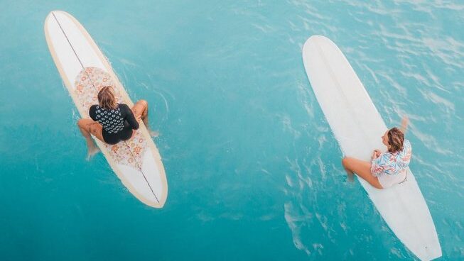 two surfers from above in bright blue water