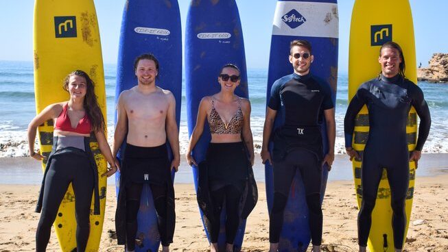 Learner surfers standing on the beach with surfboards with Tiziri Surf Maroc