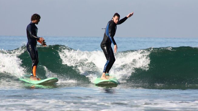 a surfer learning on a wave at a Taghazout surf camp and yoga retreat