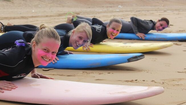 learner surfers laying on their surfboards on the beach at a Taghazout surf camp and yoga retreat