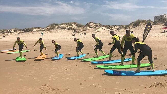 surfers learning how to surf on the sand at a surf hostel Peniche