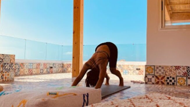 A girl posing in downward dog yoga pose during a Taghazout surf camp and yoga retreat