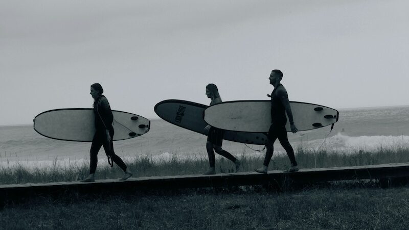 Learner surfers walking out in the water