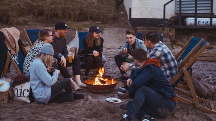 Travellers sitting around a fire on a Moroccan beach, sharing stories and enjoying why surf camps in Morocco are safe and welcoming