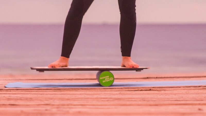 A person balancing on a board with a roller at a surf camp