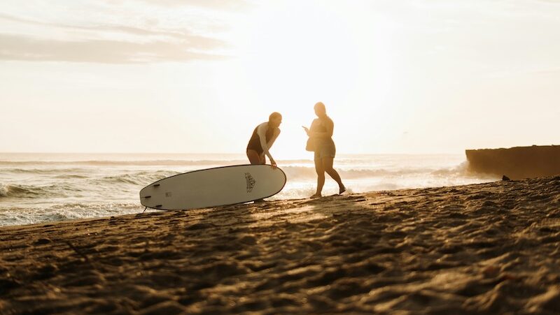 Two people enjoying surfing together in the sunset