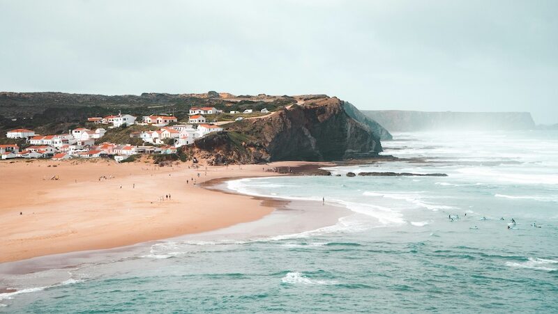 the beach of Arrifana with house and cliffs in the distance
