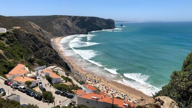 Peniche beach with lots of people laying on the beach and surfing