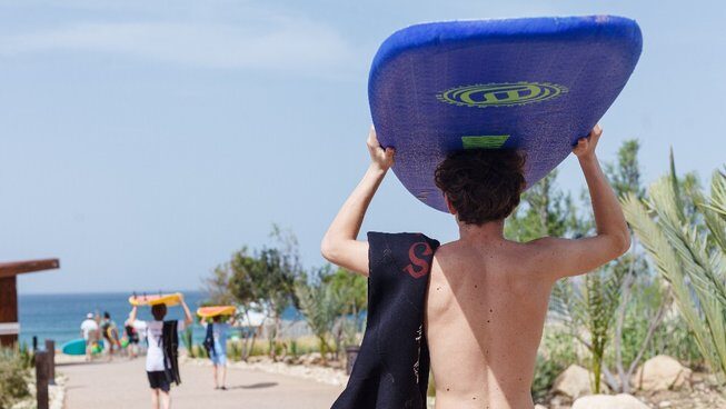 Someone carrying surfboard on his head walking to beach