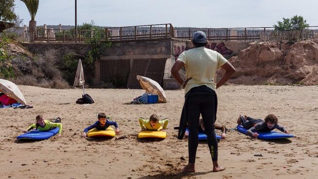 People learning how to surf on the sand with Hola Surf