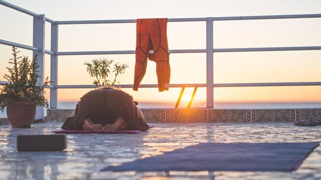 People doing yoga outside on the rooftop at Surf Coast Morocco surf camp with sun setting