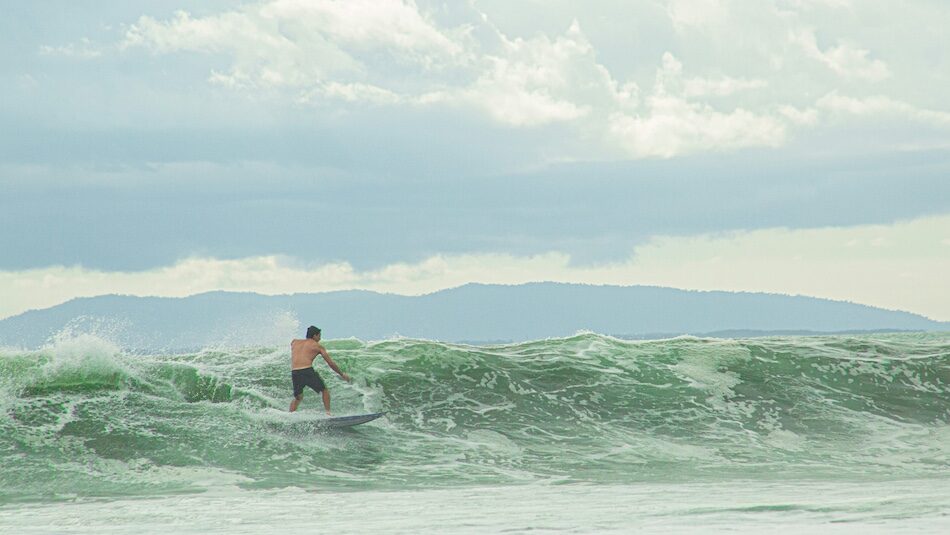 A surfer on a wave in Costa Rica with low clouds