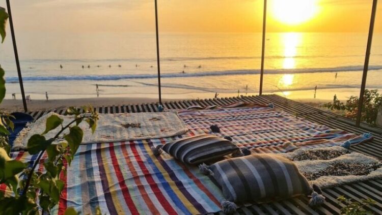 a mat an pillows on the ground at a Morocco surf camp overlooking the ocean and surf