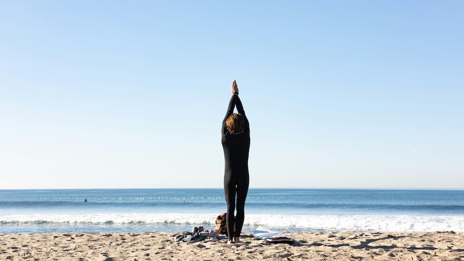6 Yoga Surf Retreat Morocco Stays Worth Booking | Your Ultimate Mind-Body Escape A person stretching on the beach at a yoga surf retreat Morocco