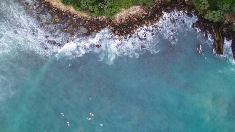 Bird's eye drone view of surfers in the water at Hiriketiya Surf Beach, waiting for waves