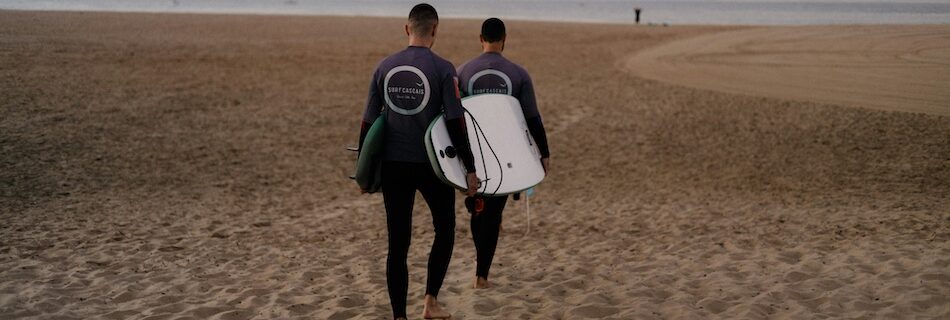 Two surfers carrying surfboards to the water when looking for Portugal vs Morocco Surf Camps