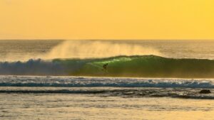 A surfer on a wave with low sun in Lombok Indonesia with best months to surf Indonesia