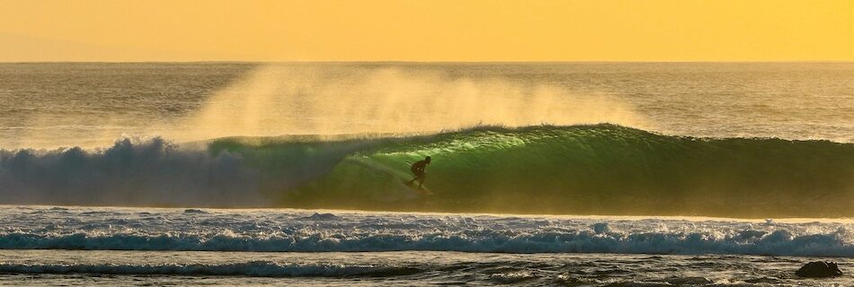 A surfer on a wave with low sun in Lombok Indonesia with best months to surf Indonesia