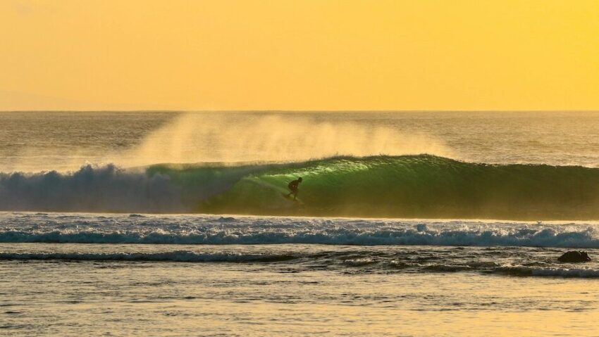 A surfer on a wave with low sun in Lombok Indonesia with best months to surf Indonesia