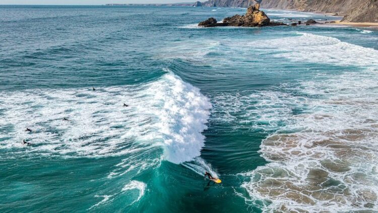 A surfer riding a wave in Sagres Portugal taken from a drone