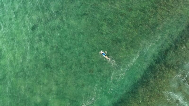 Blue water of Weligama with a surfer