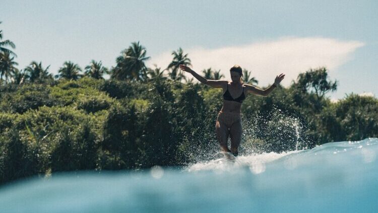 Girl surfer on a wave with palm trees