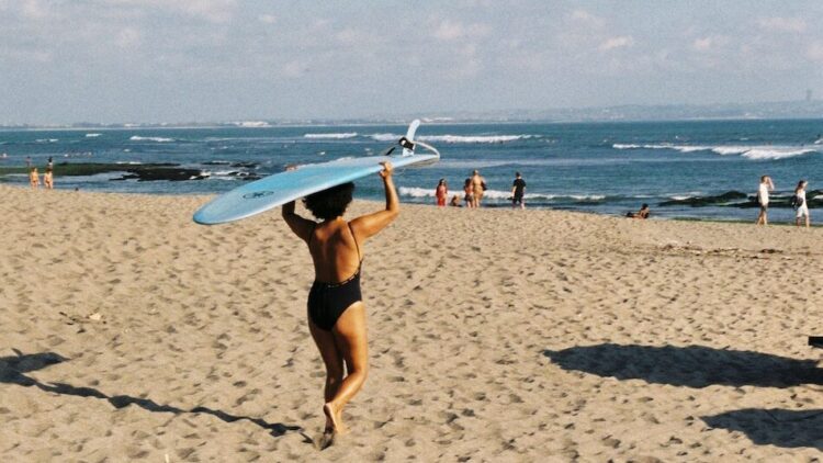 Surfer walking to the beach carrying surfboard on head