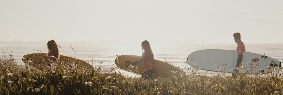 Surfers walking to the ocean with surfboards in Peniche Portugal - Portugal surf budget breakdown and travel cost