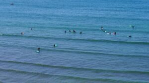 surfers in the water who were once wondering Tamraght vs Taghazout Beginner Surf Comparison