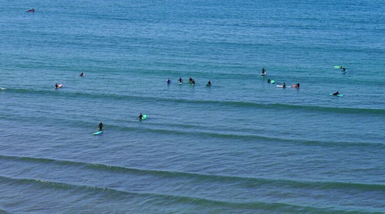 surfers in the water who were once wondering Tamraght vs Taghazout Beginner Surf Comparison