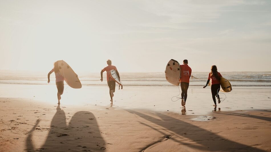 surfers walking on the beach at sunset in Peniche