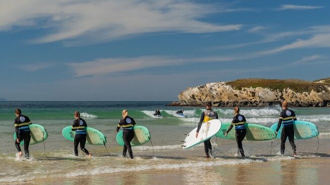 learner surfers entering the water with The Salty Peniche