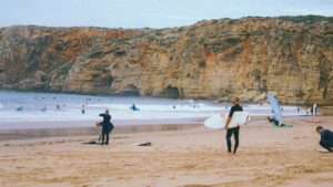 surfer on the beach thinking best week long surf camp in Portugal