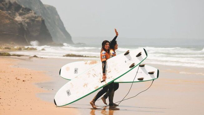two learner surfers entering the ocean